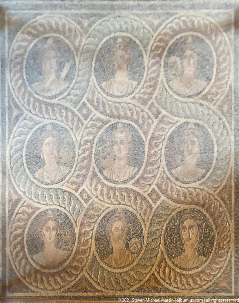 Ancient mosaic with multiple human portrait heads set in circular medallions within braided geometric borders.