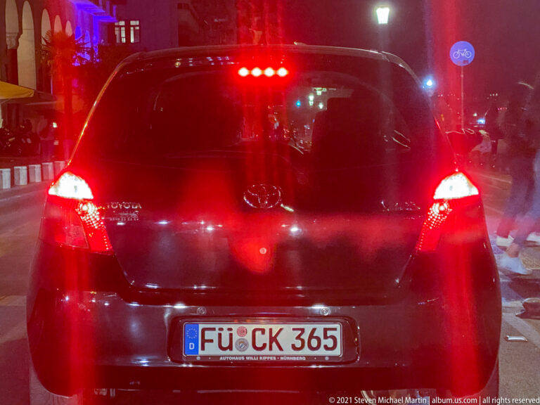 Rear of a black hatchback stopped at a red light on a Thessaloniki street at night.