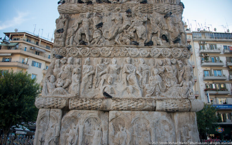 Weathered marble relief panels with crowded Roman figures and ornamental bands on the Arch of Galerius.