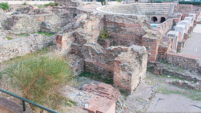 Elevated view over weathered brick-and-stone ruins with piers and fragments of curved seating.