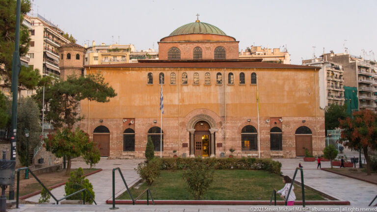Front exterior of Hagia Sophia with brick walls, arched windows, central entrance, and low dome.