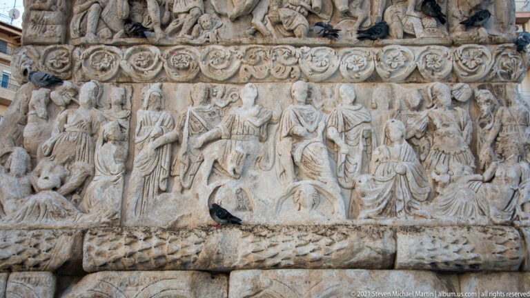Processional Roman figures carved in a weathered marble register on the Arch of Galerius.
