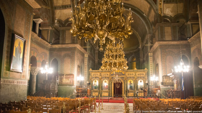 Interior of Hagia Sophia with wooden chairs, gilded chandelier, icons, and ornate iconostasis.