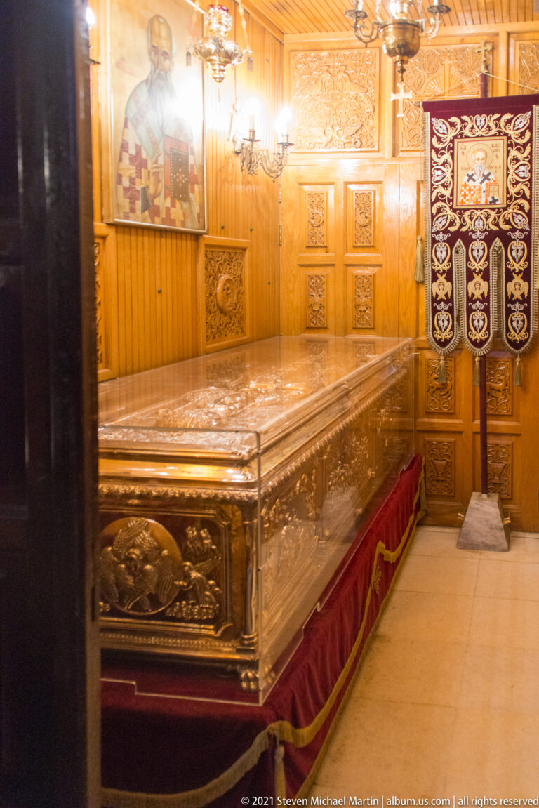 Large embossed silver shrine in a wood-paneled chapel beside an embroidered church banner.