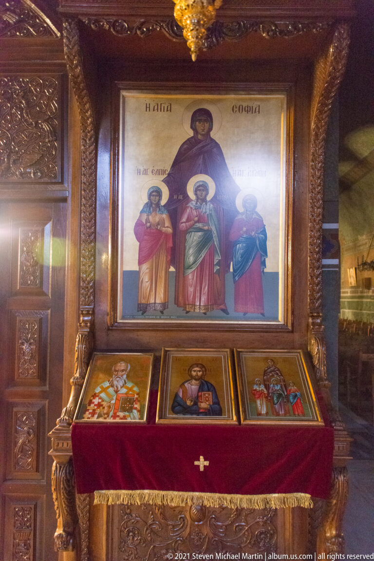 Large icon of the Virgin and saints above three smaller icons in a carved wooden shrine.