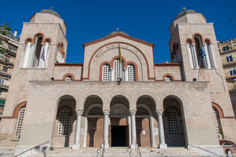 Front façade of an Orthodox church with five entrance arches, twin towers, domes, and crosses.