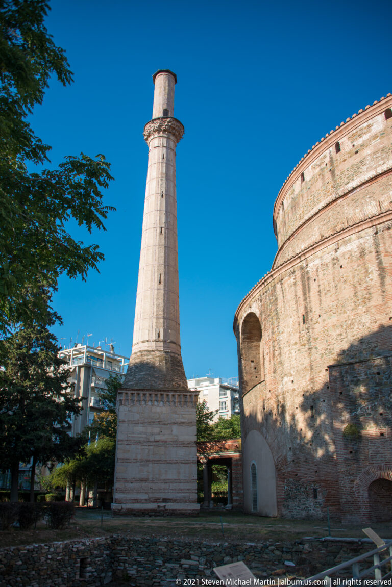 Tall pale minaret beside the curved brick wall of Thessaloniki’s Rotunda of Galerius.
