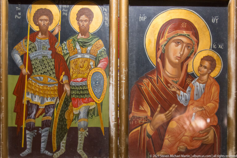 Two haloed military saints in armor beside an icon of the Virgin holding the Christ Child.
