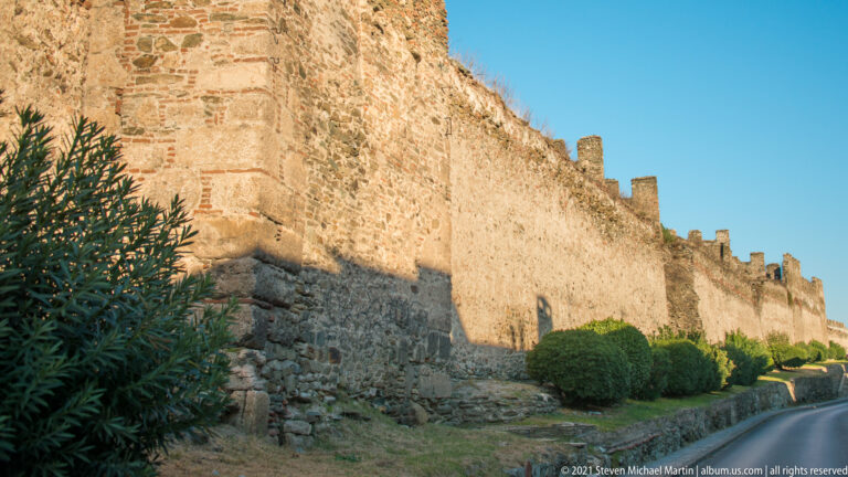 Long stone-and-brick defensive wall with crenellated parapet extending into the distance in Thessaloniki.