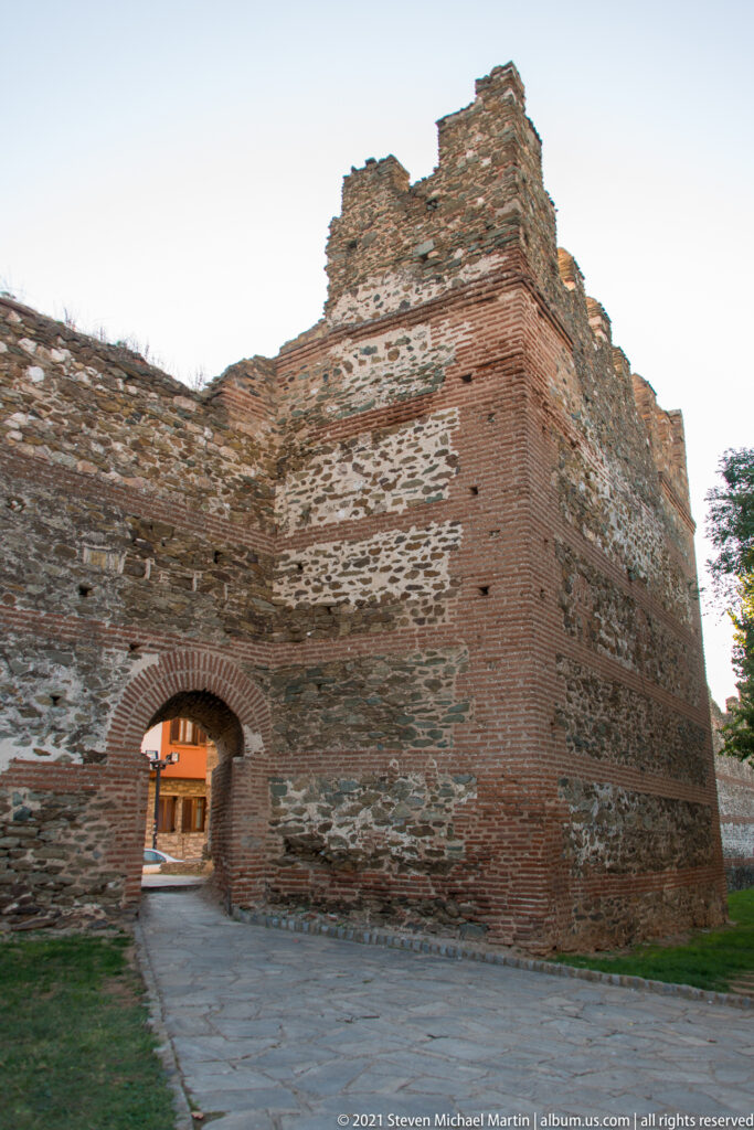 Arched pedestrian gateway through a massive stone-and-brick section of Thessaloniki's historic walls.