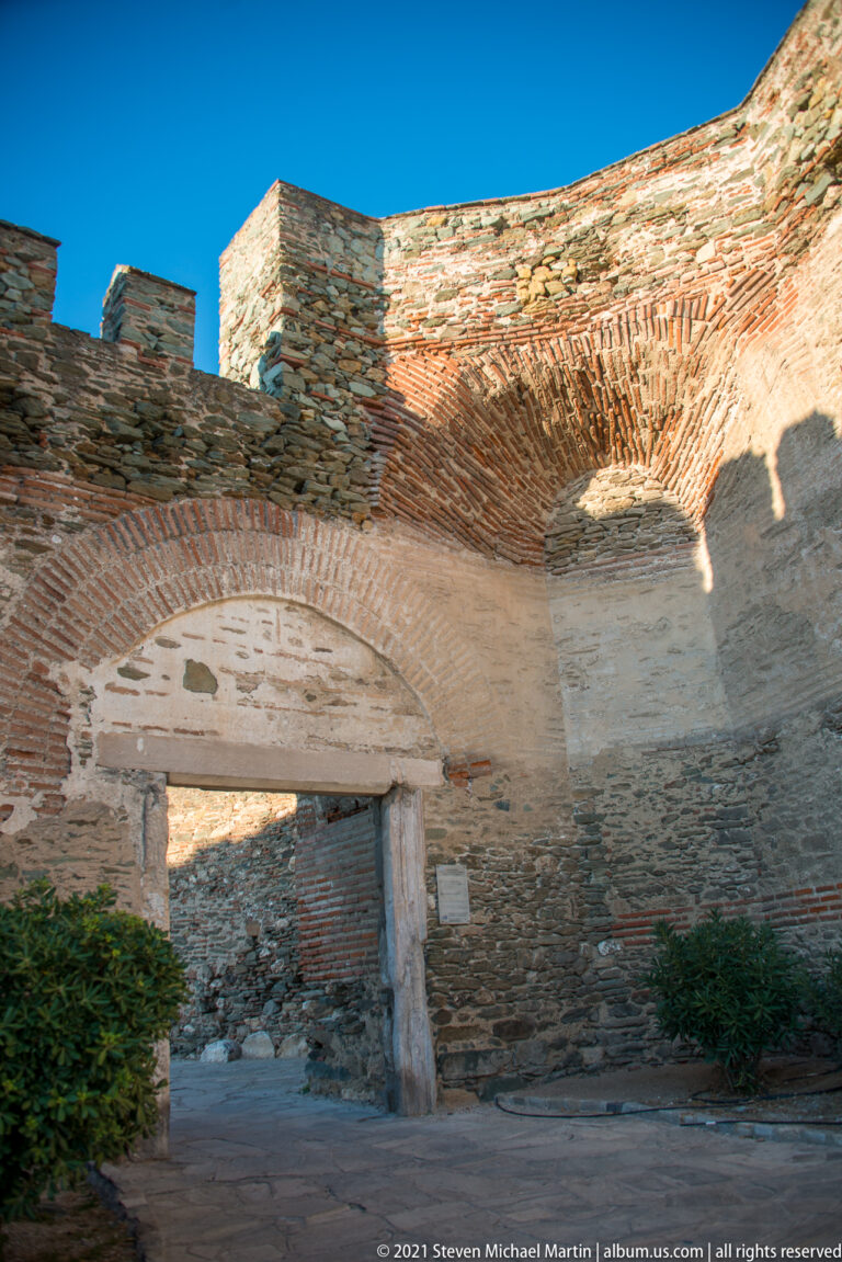 Low brick arch set within weathered stone-and-brick fortification masonry in Thessaloniki.