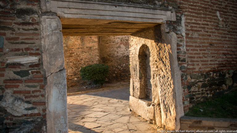 Rectangular passage through thick brick-and-stone fortification walls, opening onto a paved inner space.