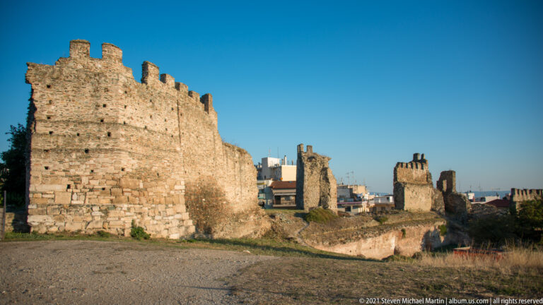 Ruined towers and connecting stone walls of the upper fortifications spread across an open area.