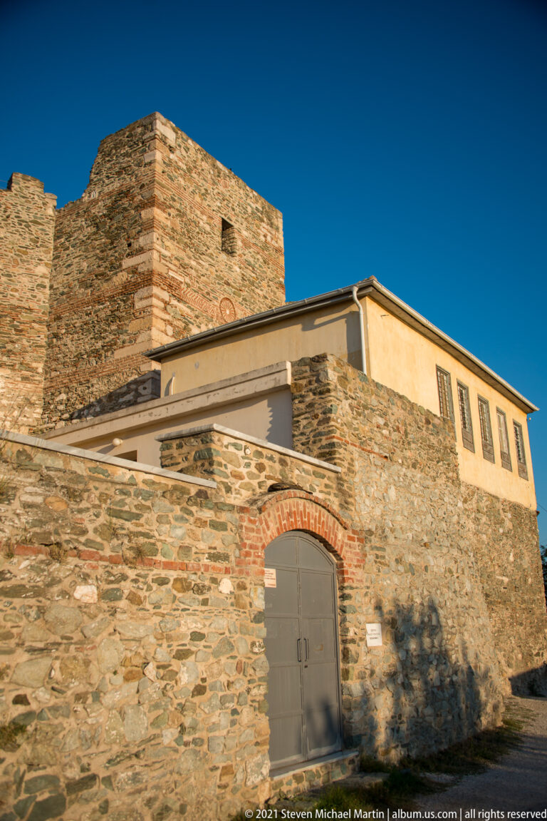 High stone Heptapyrgion wall with brick bands, later upper structure, and a small arched gate.