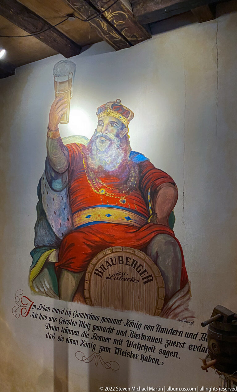 Wall painting of the crowned, white-bearded figure Blaubart in a red robe above a German verse, beneath a decorated ceiling.