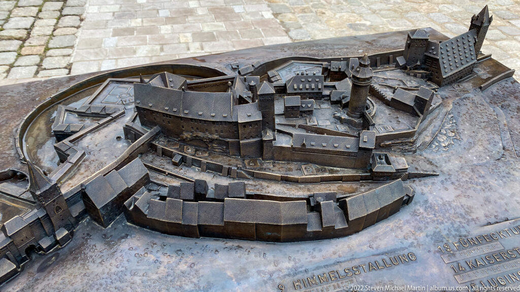 Bronze tactile model of Nuremberg Imperial Castle viewed from above, showing towers, courtyards, walls, roofs, and the fortified perimeter.