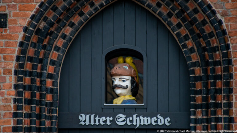 Pointed brick doorway labeled Alter Schwede, with a painted bust in a niche above the door.