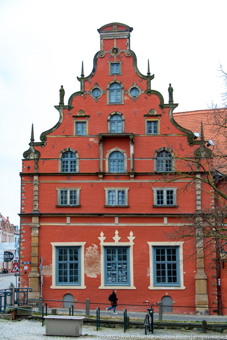 Frontal view of the Schabbellhaus red gable with curved tiers, pinnacles, oval openings, and pale-trimmed windows.