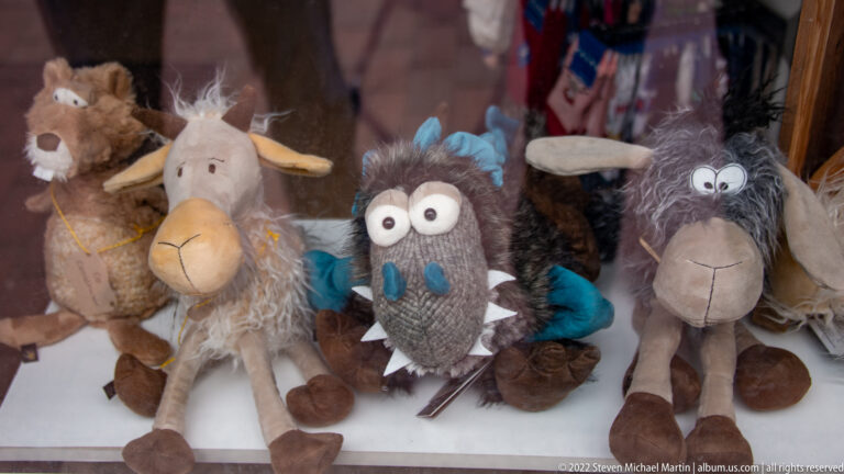 Group of shaggy plush animal toys with exaggerated eyes, long ears, horns, and smiling faces displayed together in a shop.