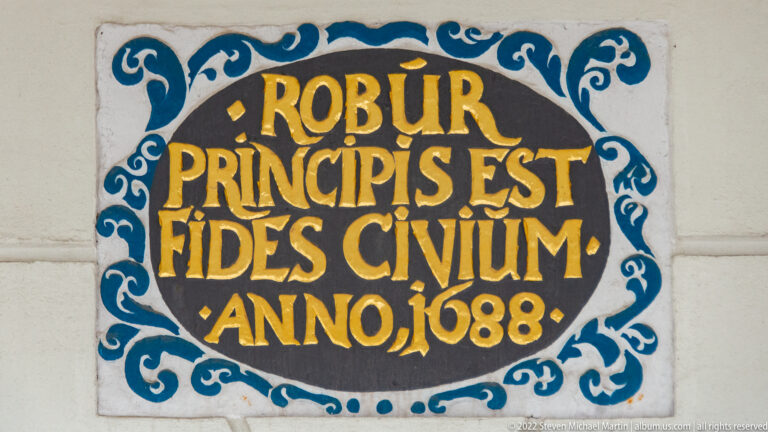 Decorative blue, white, black, and gold plaque with Latin inscription “ROBUR PRINCIPIS EST FIDES CIVIUM” and date 1688.