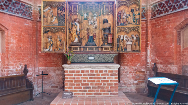 Polychrome carved Gothic altarpiece with central figures, rows of saints, narrative scenes, and open side wings.