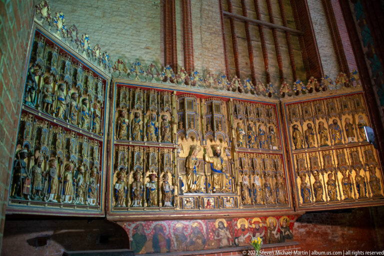 Large open Gothic altarpiece filled with rows of polychrome saints, central sacred figures, and painted lower panels.