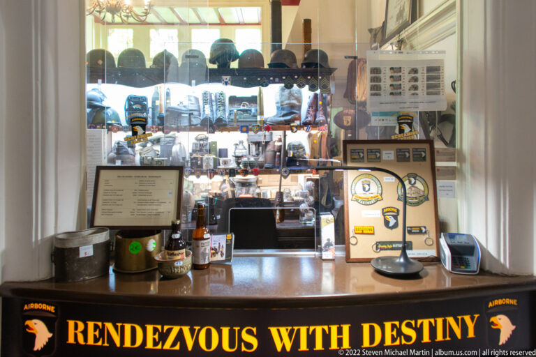 Museum counter reading RENDEZVOUS WITH DESTINY, with helmets, patches, books, and souvenirs behind glass.
