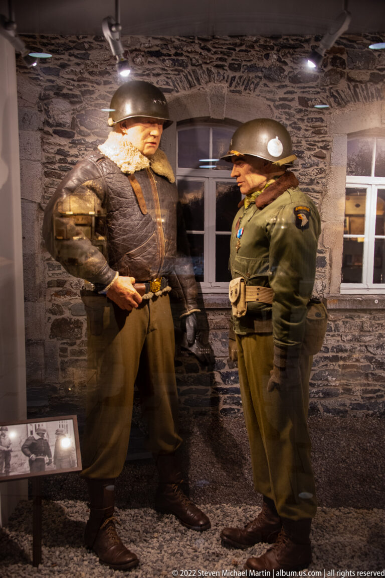 Two life-size helmeted soldier mannequins in winter uniforms facing each other in a dark museum diorama.