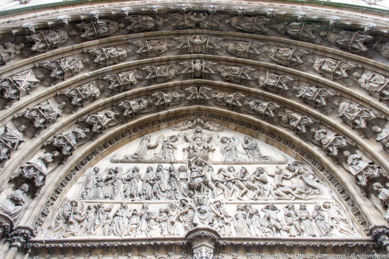 Pointed cathedral portal densely carved with rows of saints, angels, and narrative reliefs in the archivolts and tympanum.