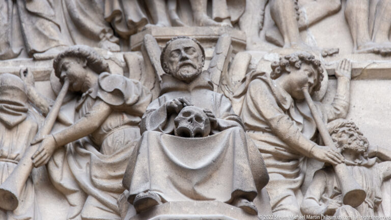 Close stone relief with haloed central figure, skull motif, and surrounding carved figures from the cathedral portal.