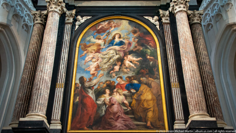 Rubens’s Assumption of the Virgin mounted in a tall dark altar frame between veined columns inside Antwerp Cathedral.