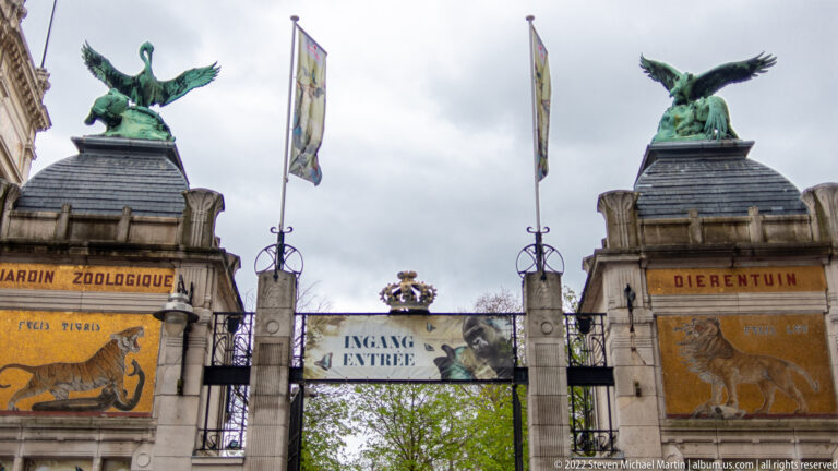 Antwerp Zoo entrance gate with animal sculptures, painted panels, and Ingang/Entrée signage.