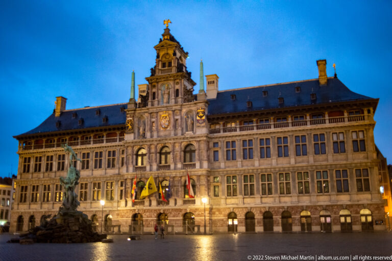 Wide night view of Antwerp City Hall with the Brabo Fountain standing on the open Grote Markt.