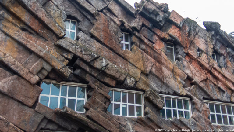 Themed brown rockwork facade with ledges, crevices, and rectangular windows set into the artificial cliff surface.