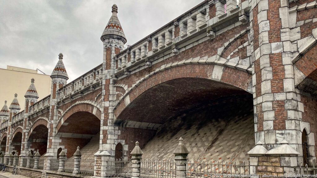 Decorative brick-and-stone railway viaduct with broad arches and small turret-like finials in Antwerp.