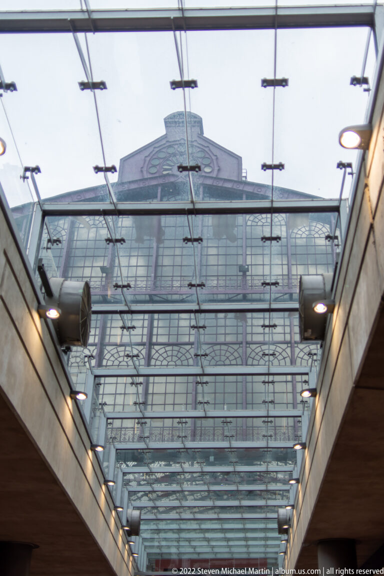 Glass canopy with metal fittings leading toward the upper facade of Antwerp-Central Station.