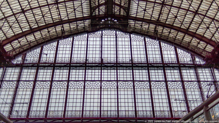 Arched iron-and-glass train shed with a huge gridded end window inside Antwerp-Central Station.