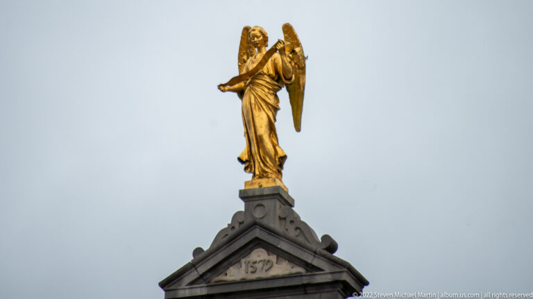 Gilded winged female figure crowning a triangular stone gable marked 1579.