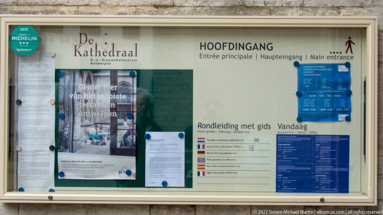 Glazed Cathedral of Our Lady information board marked HOOFDINGANG, with multilingual visitor notices and guided-tour information.