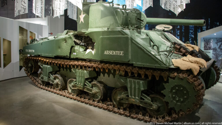 Olive-drab Sherman tank named Absentee with white star, turret, gun, tracks, and field gear draped over the hull.