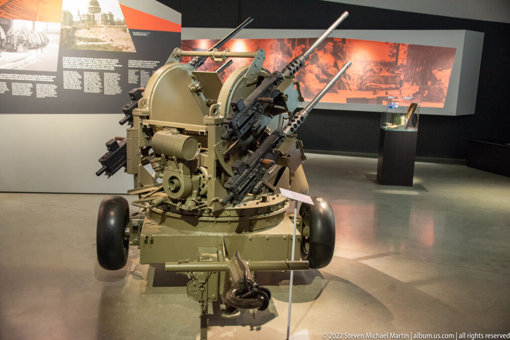 Restored wheeled anti-aircraft gun with multiple elevated barrels displayed inside the museum.