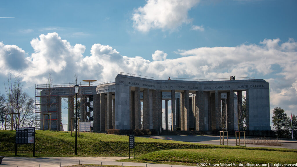 Exterior of the Mardasson Memorial with stone colonnade, U.S. state names, and scaffolding at left.
