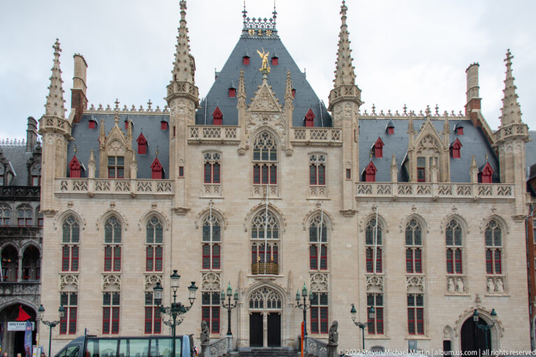 Provinciaal Hof in Bruges with pale Gothic Revival façade, pointed windows, pinnacles, and steep slate roof.