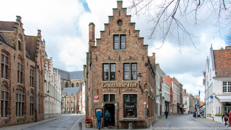 Gruuthuse Hof brick stepped-gable building on a narrow Bruges street with historic buildings receding behind.
