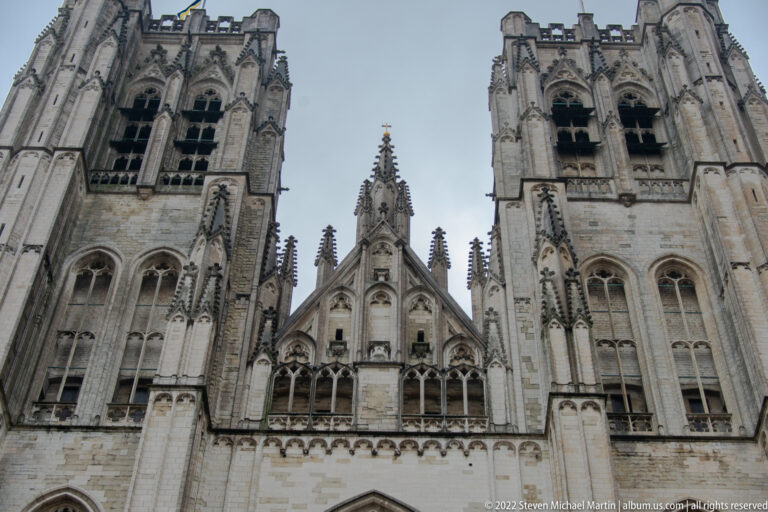 Upward view between the cathedral’s twin towers, showing Gothic gables, tracery, pinnacles, and carved stone details.