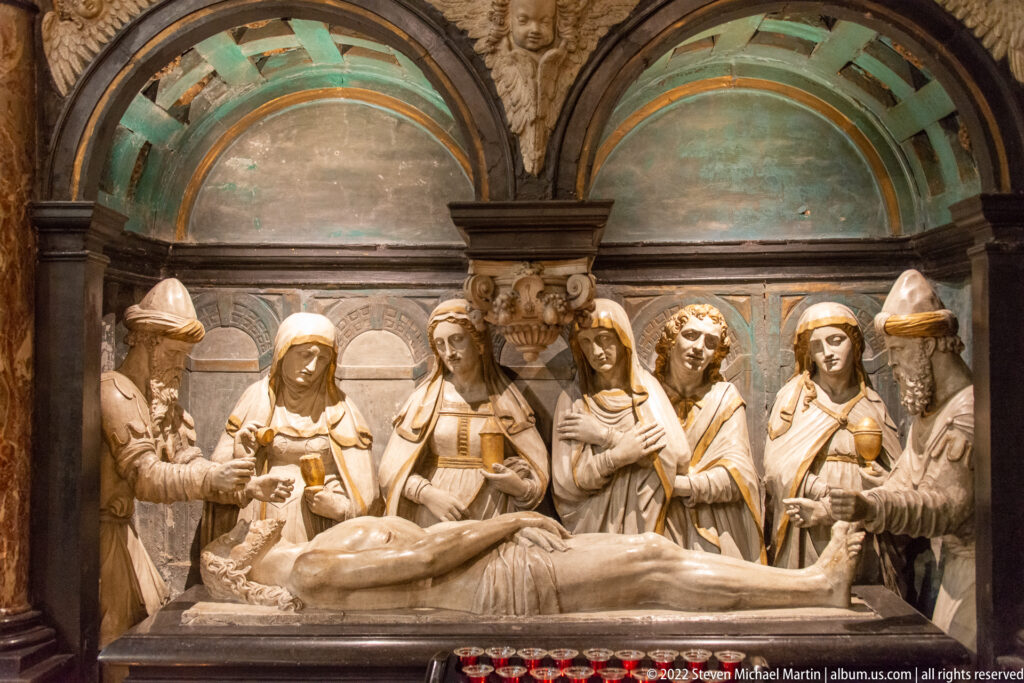 Stone Entombment group with mourners standing behind the recumbent body of Christ beneath a shallow architectural canopy.