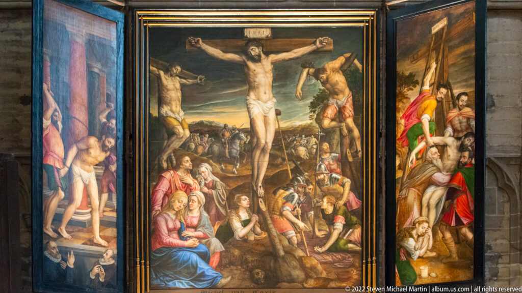 Multi-panel painted altarpiece with the Crucifixion in the center and crowded narrative scenes extending onto side panels.