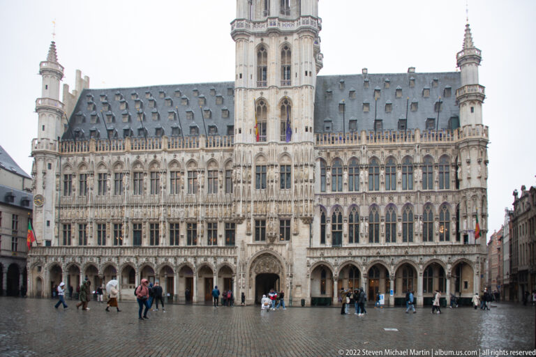 Full Gothic façade of Brussels Town Hall on the Grand-Place, with its tall central tower above arcades and rows of windows.
