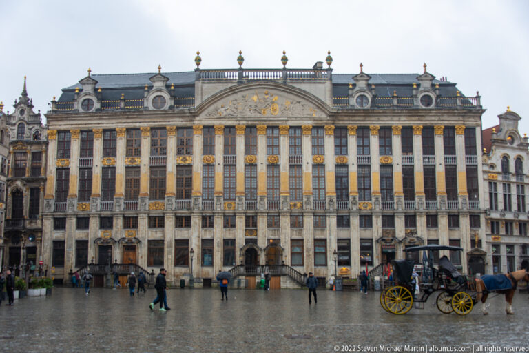 Long gilded and stone façade of the Maison des Ducs de Brabant on the Grand-Place, with a horse-drawn carriage at right.