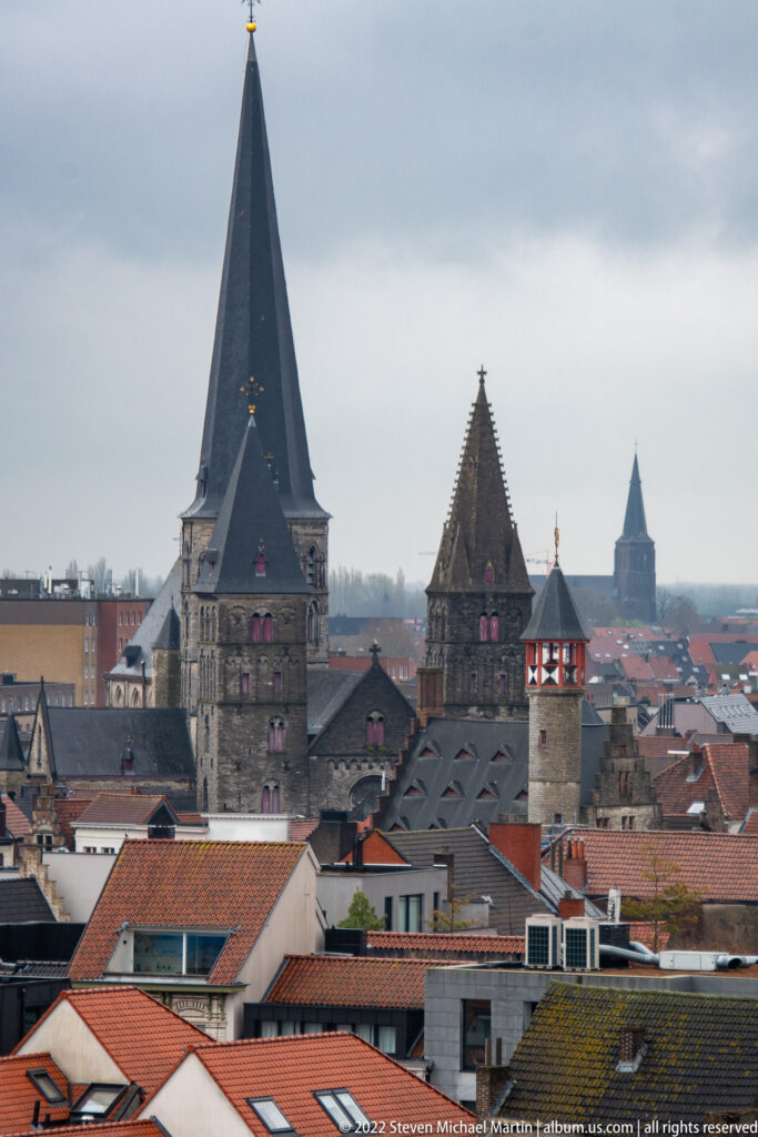 Gray stone towers of Gravensteen with steep roofs rising above red-tiled rooftops in Ghent.